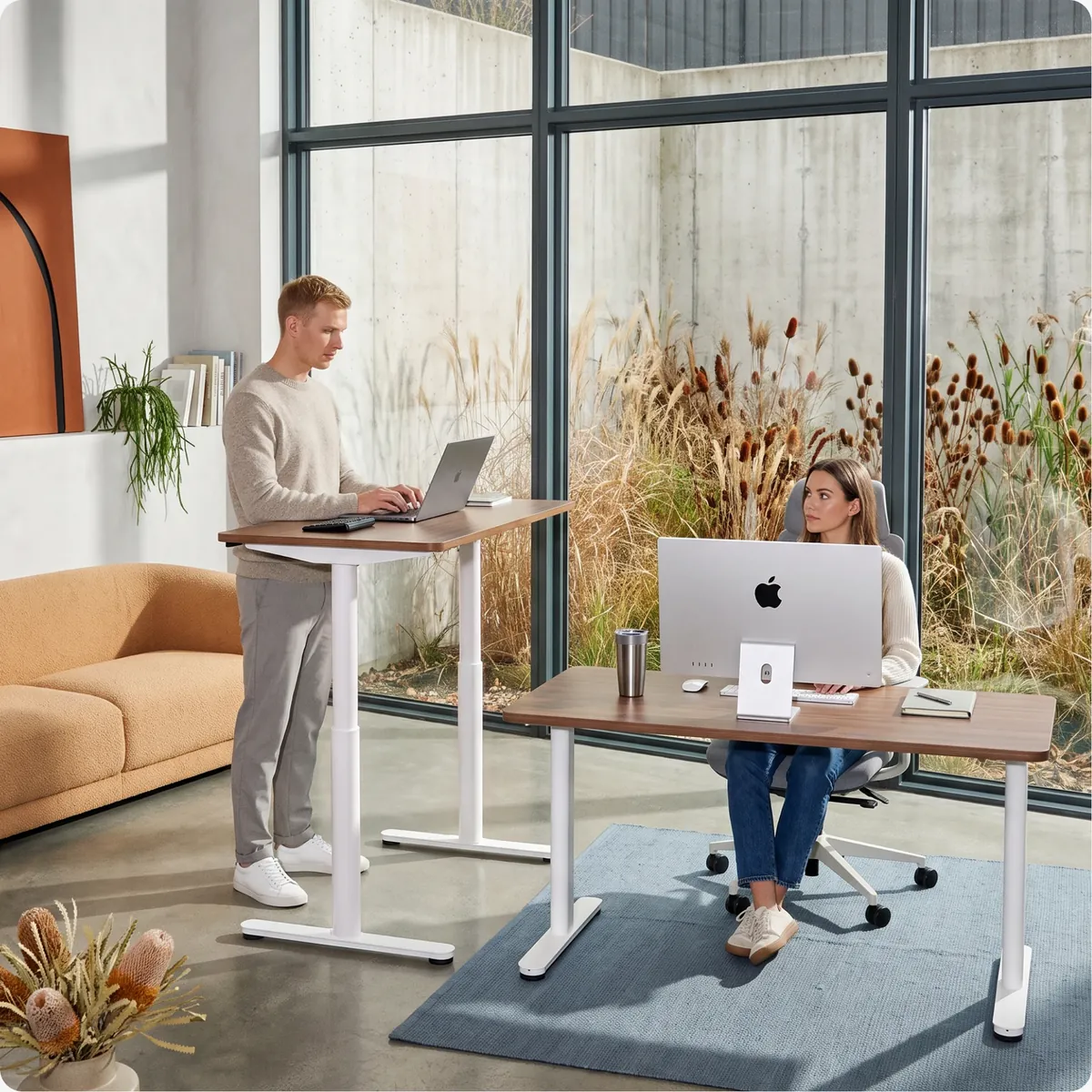 Two people at Ergonix desks at different heights: adjustable height